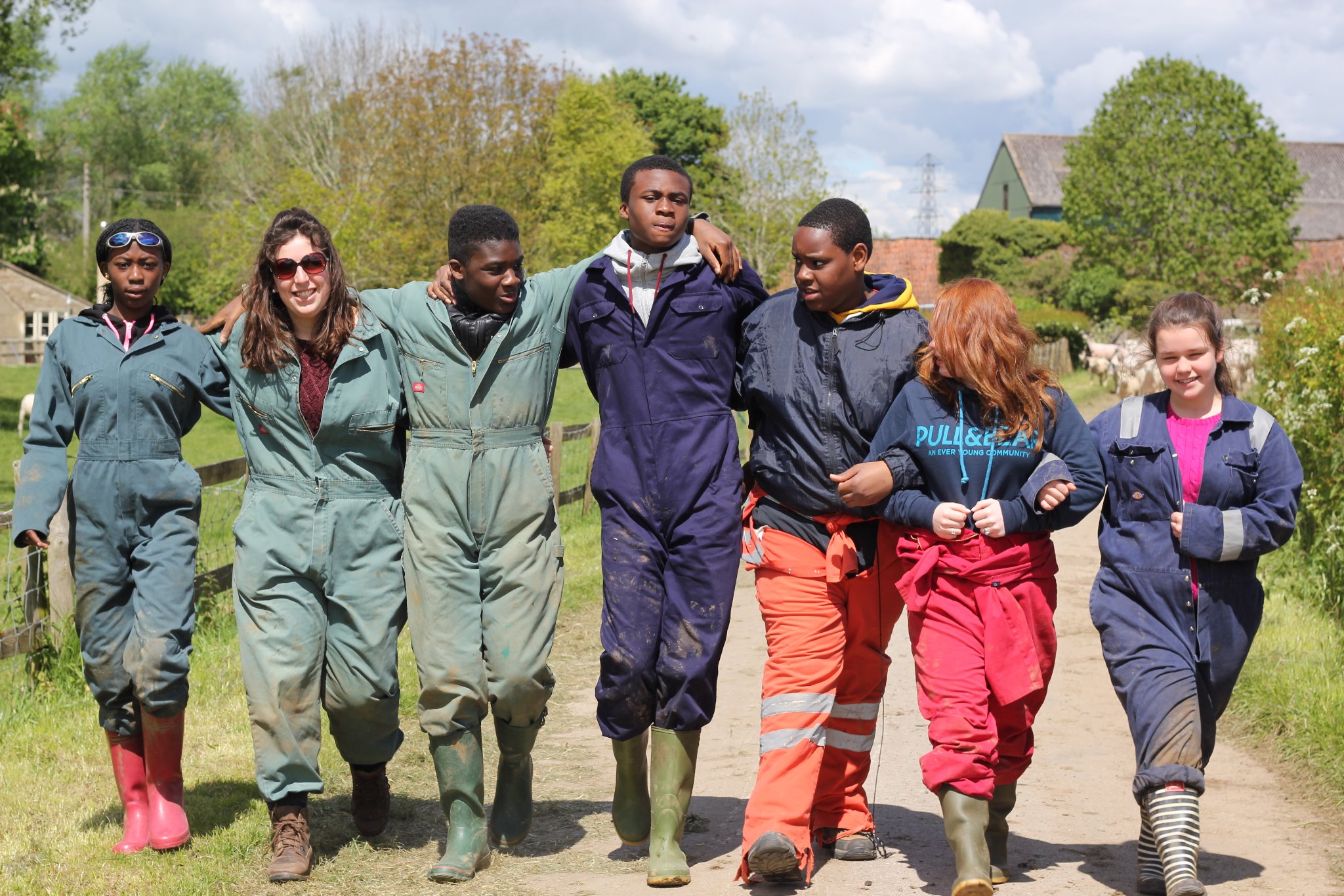 Young people in overalls walking together on a farm track after a day of outdoor learning